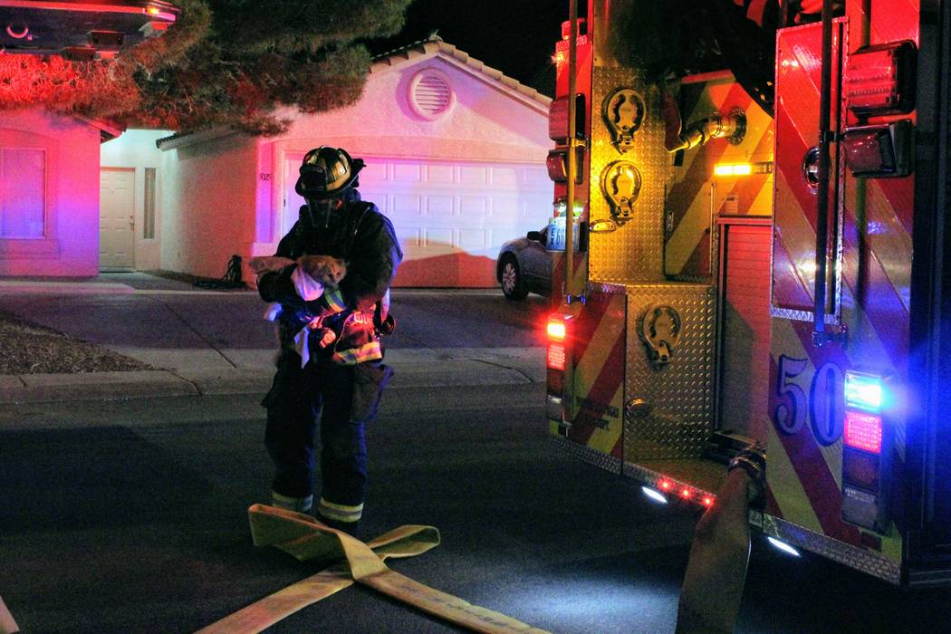 A North Las Vegas firefighter carries a cat out of a home Monday morning after a fire at 5920 N. Vista Del Rancho Way. (Max Michor/Las Vegas Review-Journal)