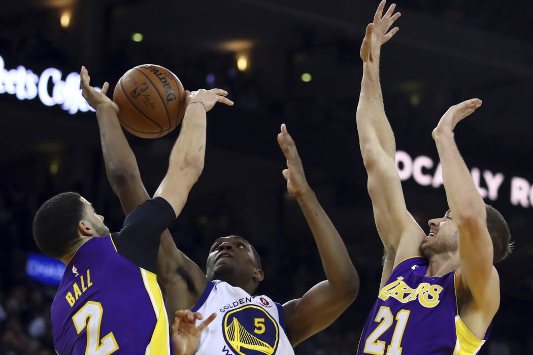 Golden State Warriors' Kevon Looney, center, is guarded by Los Angeles Lakers' Lonzo Ball (2) and Travis Wear (21) during the second half of an NBA basketball game Wednesday, March 14, 2018, in Oa ...