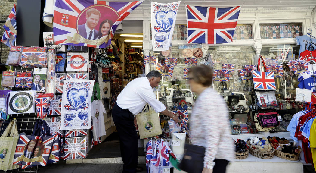 A woman passes a shop window decorated with wedding memorabilia in Windsor, England, Monday, May 14, 2018. Preparations are being made in the town ahead of the wedding of Britain's Prince Harry an ...