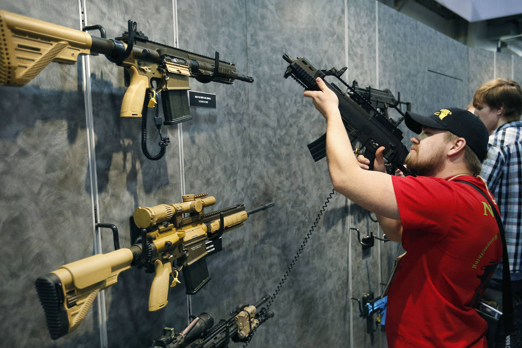 FILE - In this Jan. 19, 2016 file photo, Nolan Hammer looks at a gun at the Heckler & Koch booth at the Shooting, Hunting and Outdoor Trade Show in Las Vegas. Nearly two-thirds of Americans ex ...