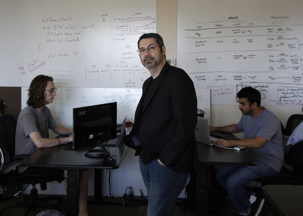 Rick Duggan, CEO at Concierge Software Design, poses for photo as Triston Jones, left, and Kandarp Dave, both senior software engineers, work on their project at their Las Vegas office on Friday, ...