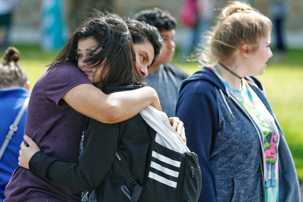 Santa Fe High School freshman Caitlyn Girouard, center, hugs her friend outside the Alamo Gym where students and parents wait to reunite following a shooting at Santa Fe High School Friday, May 18 ...
