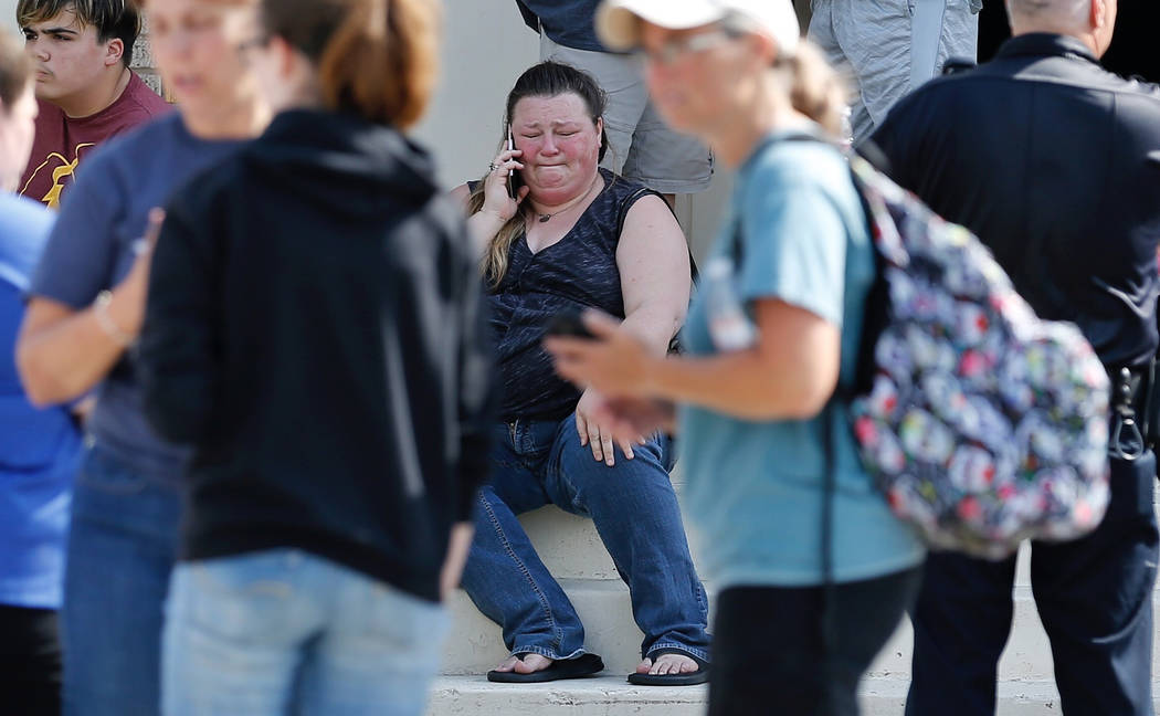 A woman reacts while making a phone call outside the Alamo Gym where parents wait to reunite with their children following a shooting at Santa Fe High School in Santa Fe, Texas, on Friday, May 18, ...