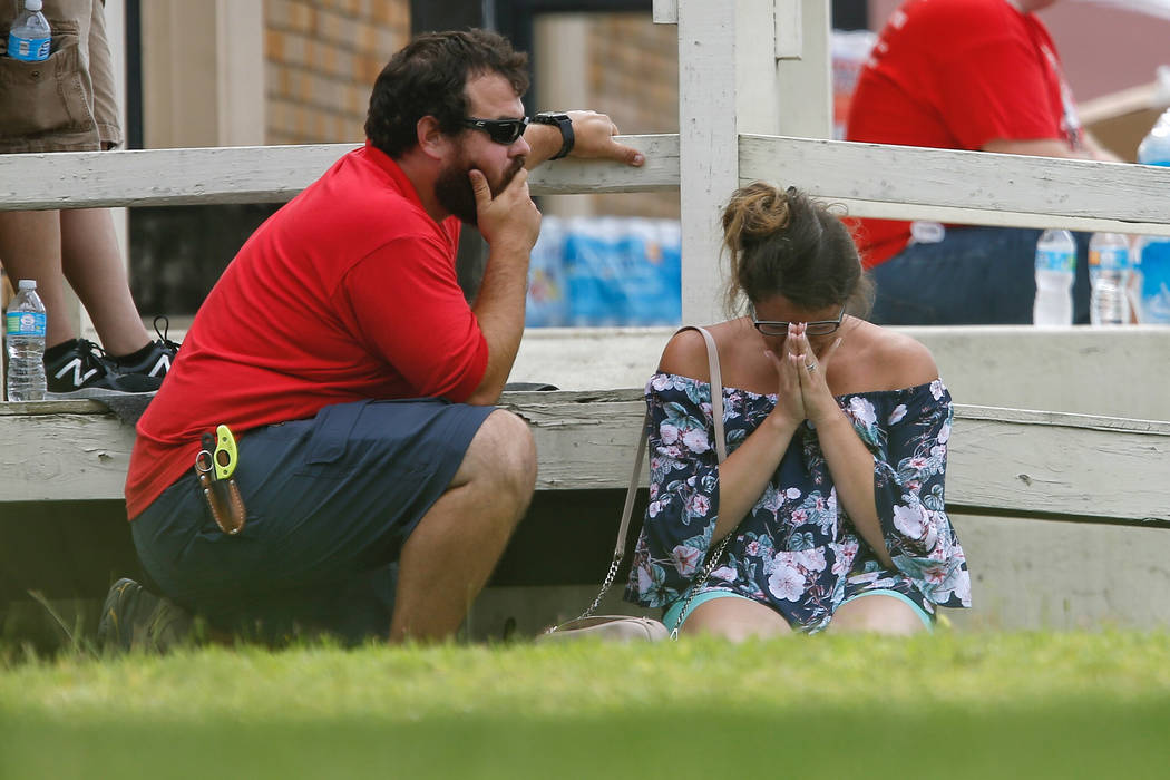 A woman prays in the grass outside the Alamo Gym where parents wait to reunite with their kids following a shooting at Santa Fe High School Friday, May 18, 2018, in Santa Fe, Texas. (Michael Ciagl ...