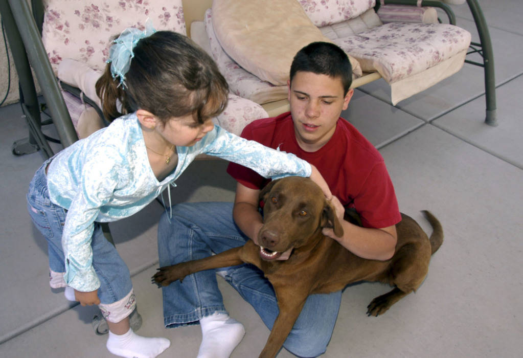 CN/VIEW--Seven year old Jessica Lindley pets the family dog, Cleo as her brother, Rayn holds the canine in their Las Vegas backyard, Thursday, 4/19/07. Jessica has taken 22 flights on Miracle Flig ...