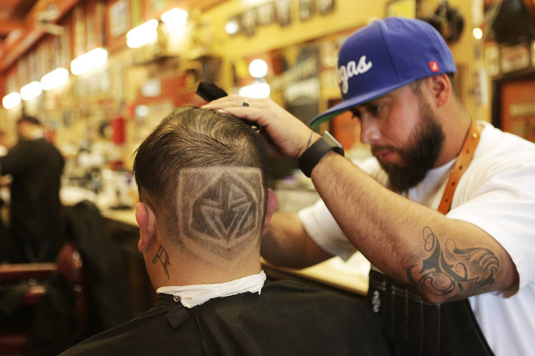 Moises “Moy The Barber” Alvarez, right, owner of the Goodtimes Barber Shop & Shave Parlor on Sahara in Las Vegas, puts finishing touches on a Golden Knights haircut for Fernando ...