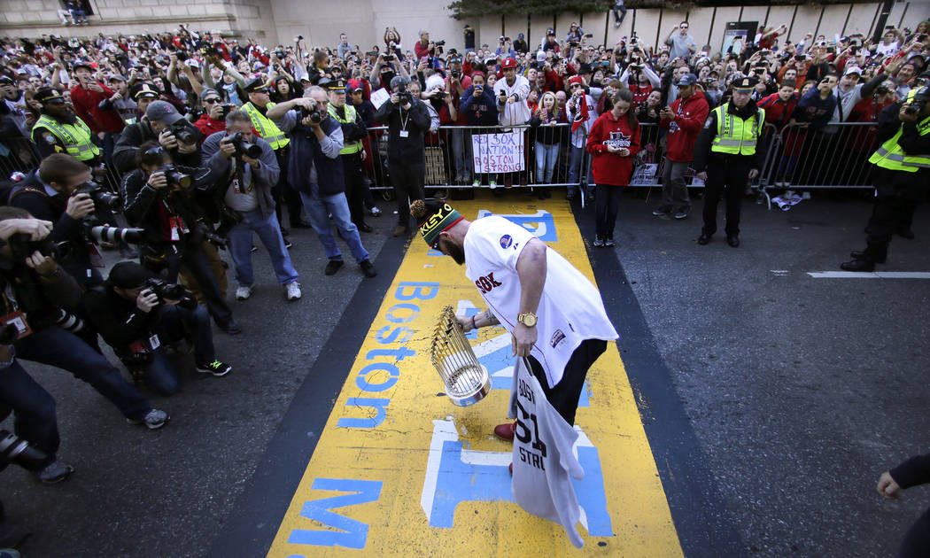 Boston Red Sox's Jonny Gomes puts the 2013 World Series trophy and a team jersey on the finish line of the Boston Marathon, in honor of those affected by the bombings, as they stopped the parade i ...