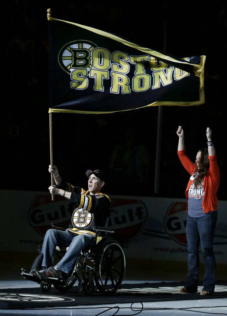 Richard Donohue, the Massachusetts Bay Transportation Authority officer wounded during the shootout with the Boston Marathon bombing suspects, waves a "Boston Strong" banner as his wife, ...