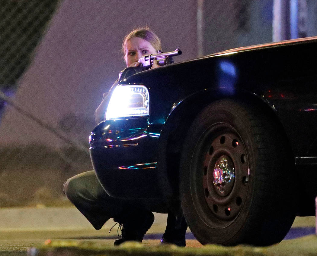 A police officer takes cover behind a police vehicle during a mass hooting near Mandalay Bay in Las Vegas on Oct. 1, 2017. (AP Photo/John Locher)