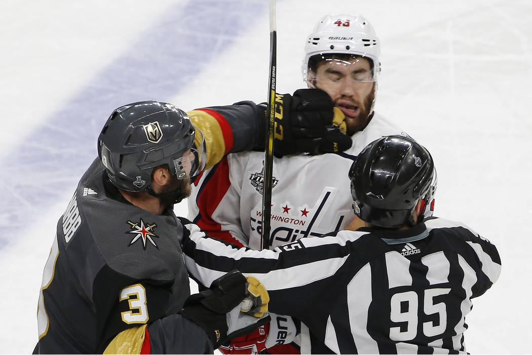 Vegas Golden Knights defenseman Brayden McNabb, left, hits Washington Capitals right wing Tom Wilson as linesman Jonny Murray tries to break it up during the third period in Game 1 of the NHL hock ...