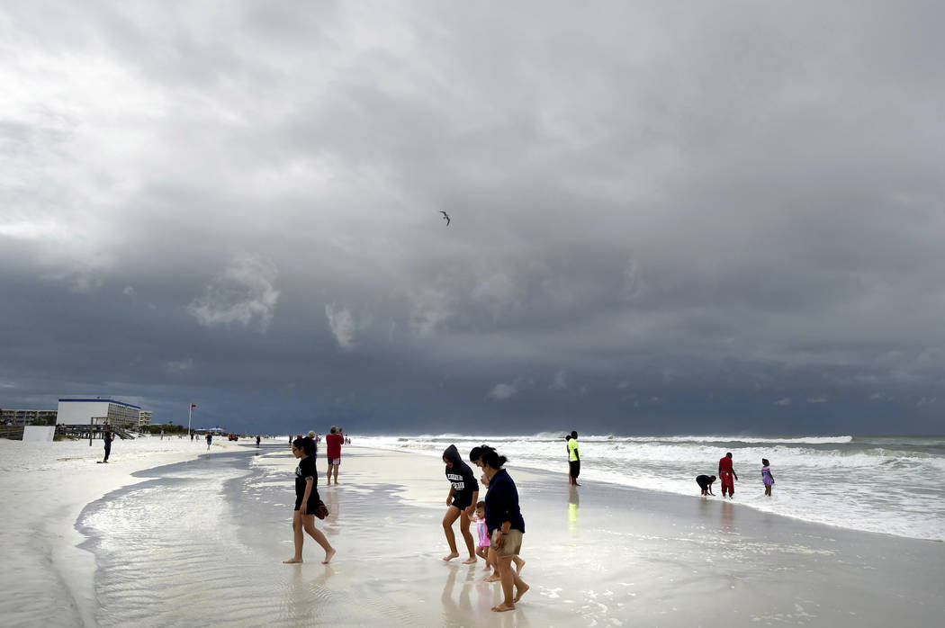 Beachgoers walk on Okaloosa Island in Fort Walton Beach, Fla., Monday, May 28, 2018, as Subtropical Storm Alberto approaches the Gulf Coast. The storm's gusty rain and brisk winds roiled the seas ...