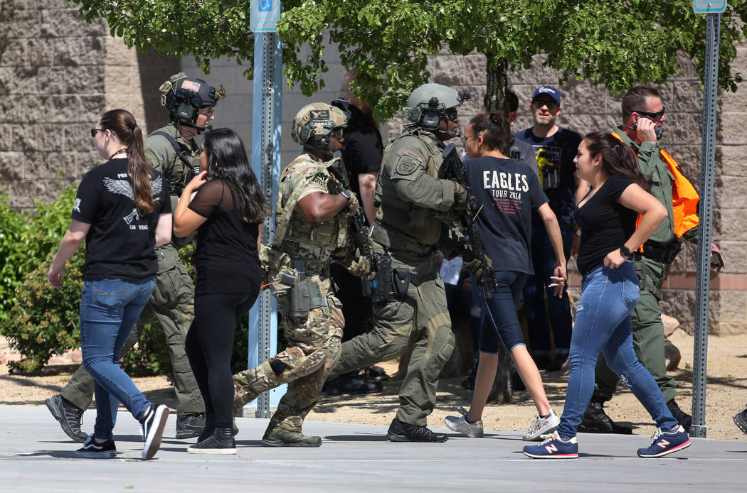 A Las Vegas SWAT team members aim their weapons as they approach Shadow Ridge High School where a mass shooting drill, coordinated by the Metropolitan Police Department and the various agencies in ...