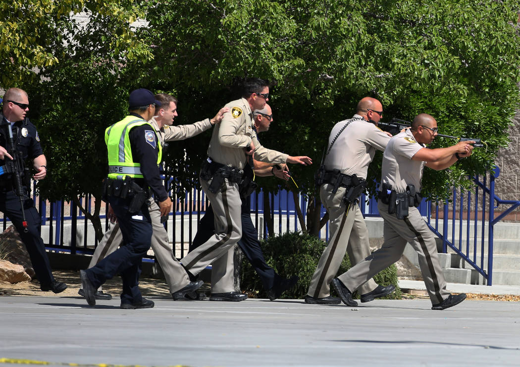 Las Vegas police officers aim their weapons as they approach Shadow Ridge High School where a mass shooting drill, coordinated by the Metropolitan Police Department and the various agencies in the ...