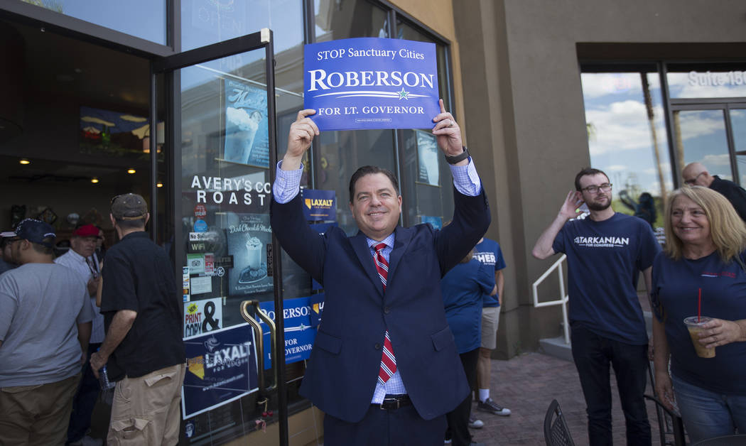 Senate Minority Leader Michael Roberson holds his own sign up to show the protestors at a Republican "Get-Out-The-Vote" campaign at Avery's Coffee Shop in Las Vegas, Wednesday, May 30, 2 ...