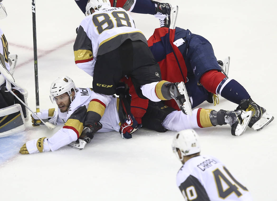Washington Capitals left wing Alex Ovechkin (8) and Golden Knights defenseman Nate Schmidt (88) fall on top of Golden Knights defenseman Brayden McNabb (3) during the first period of Game 3 of the ...