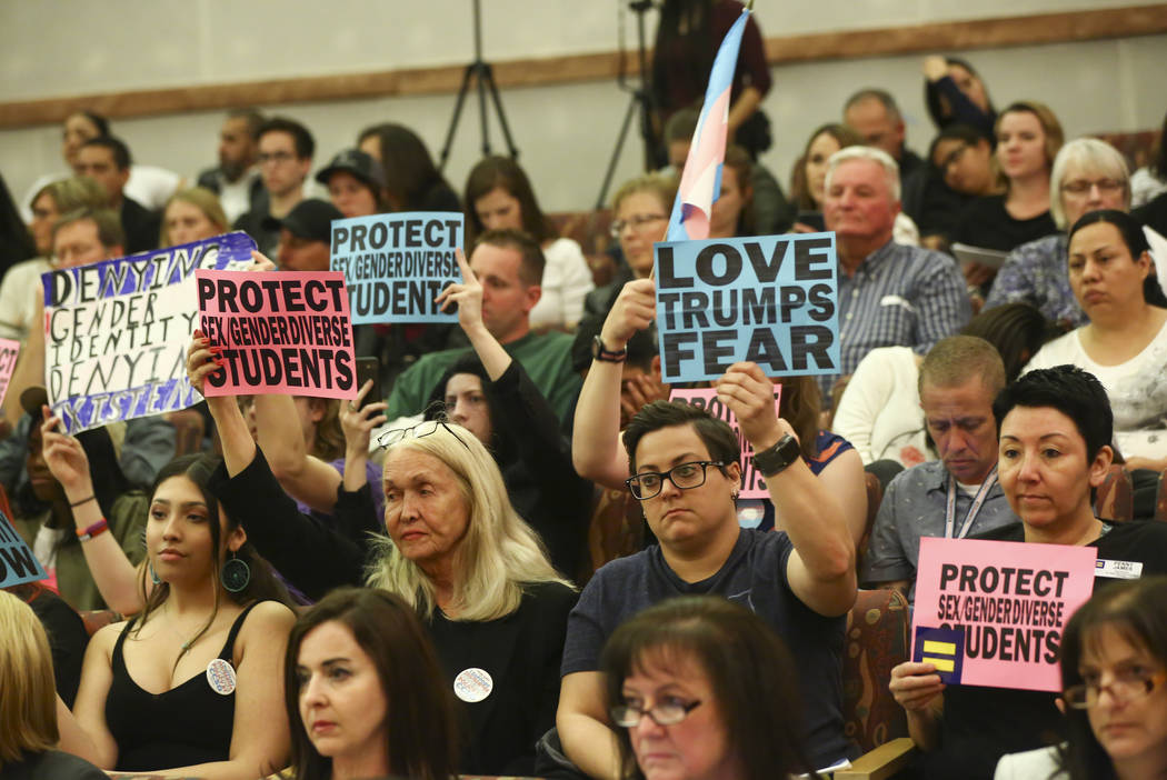 Attendees hold up signs in support of a gender-diverse policy for the school district during a Clark County School District Board of Trustees meeting at the County Government Center in Las Vegas o ...