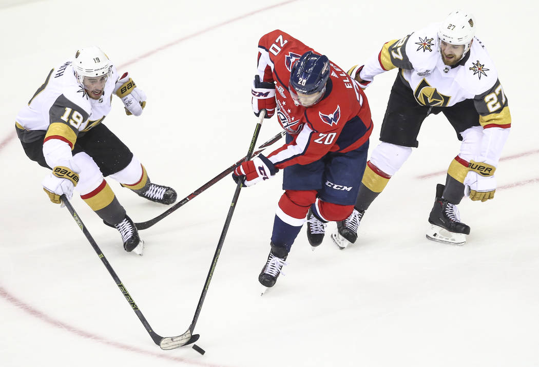 Golden Knights right wing Reilly Smith (19) and Washington Capitals center Lars Eller (20) battle for the puck next to Golden Knights defenseman Shea Theodore (27) during the second period of Game ...