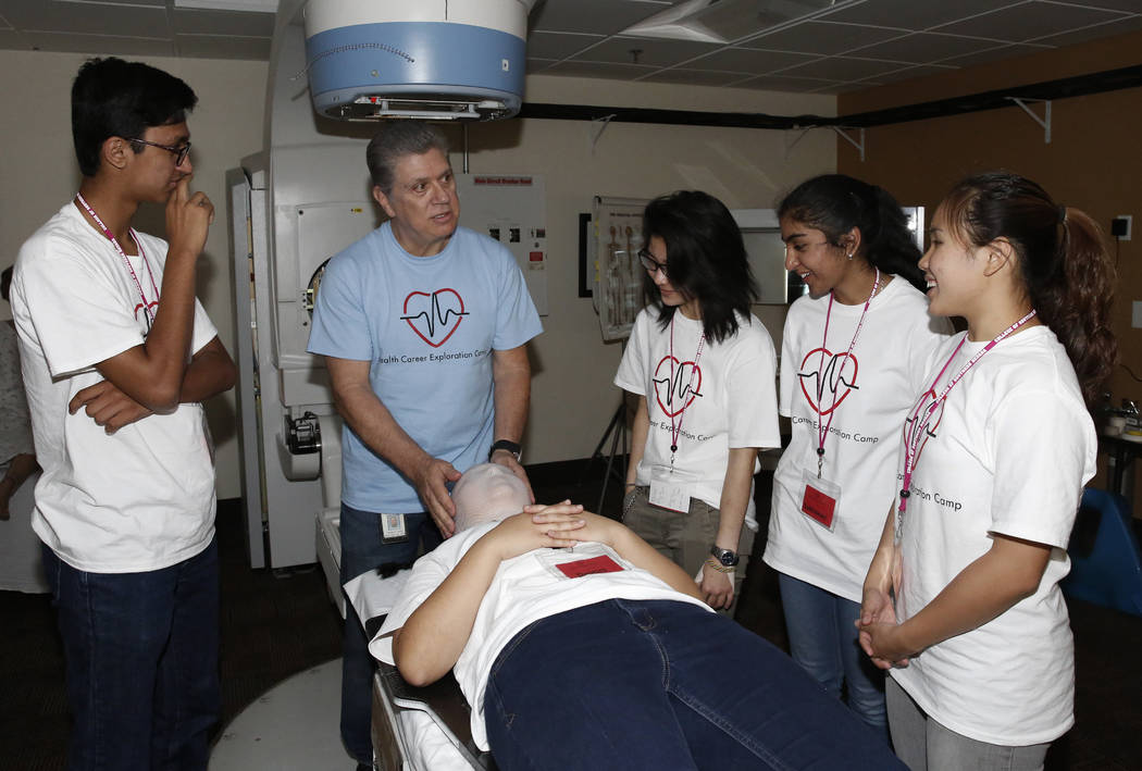 James Godin, chair, Dental Diagnostic and Rehab Service at College of Southern Nevada, demonstrates how a patient would undergo a radiation treatment to Clark County High School students, Ameya Si ...