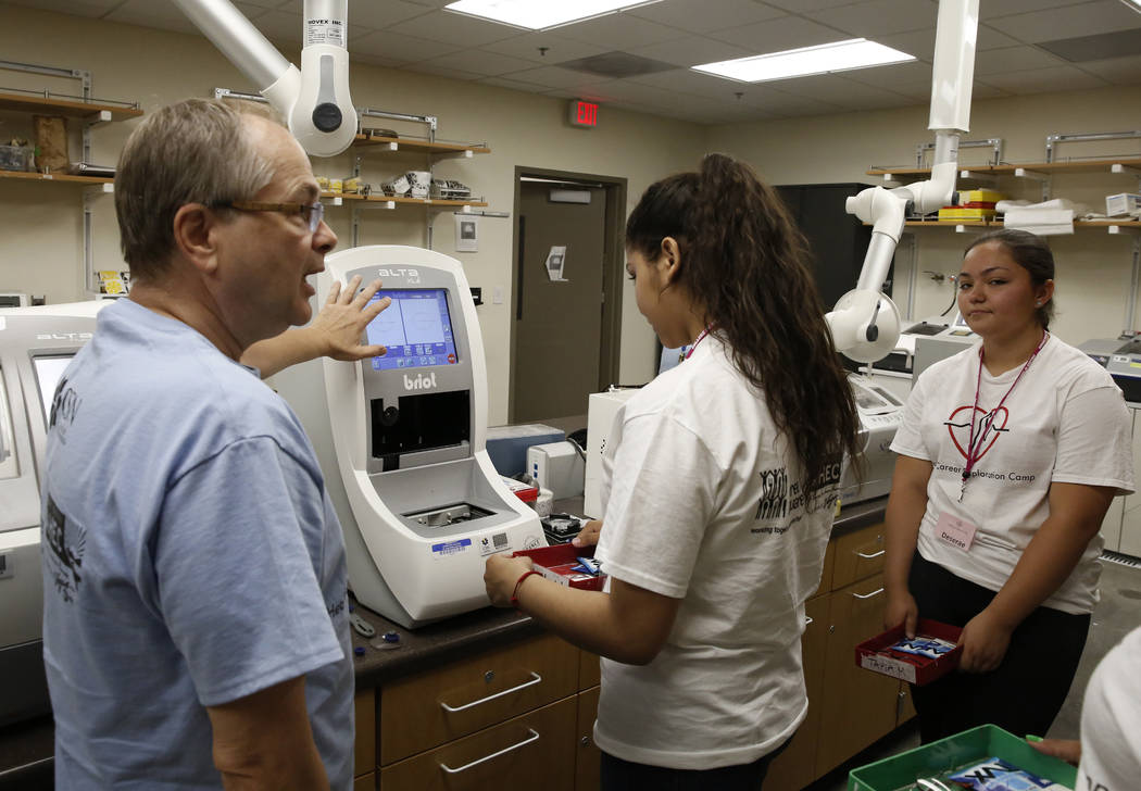 Clark County High School students, Maryanna Muñoz, center, and Deserae Olsen listen as Scott Helkaa, left, program director, Ophthalmic Technology at College of Southern Nevada, demonstrates ...