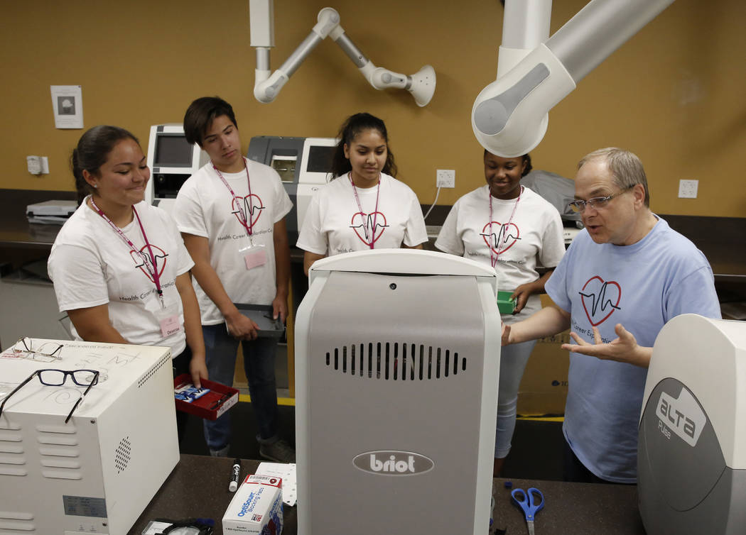 Clark County High School students, Deserae Olsen, left, Cristobal Luna, Maryanna Muñoz, Kaelyn Yarbrough, second right, listen as Scott Helkaa, right, program director, Ophthalmic Technology ...