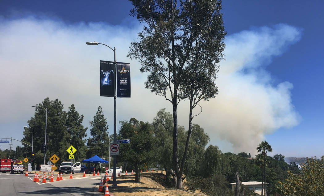 A large plume of smoke rises over Benedict Canyon in Los Angeles in the hills surrounded by Beverly Hills, Calif., on Tuesday, June 12, 2018. More than 100 firefighters raced to the hills overlook ...