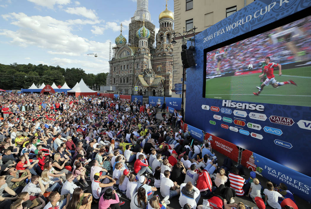 People watch on a huge screen the 2018 soccer World Cup match between Russia and Saudi Arabia at a fan zone in St.Petersburg, Russia, Thursday, June 14, 2018. (AP Photo/Dmitri Lovetsky)