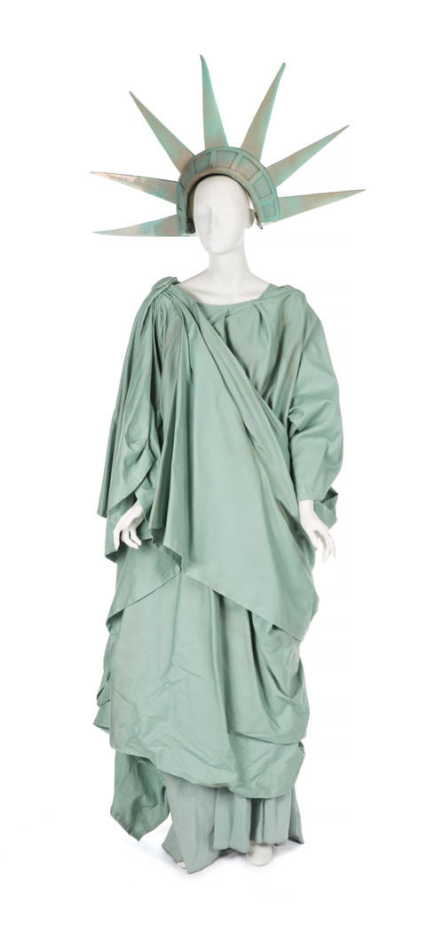 A multilayered floor-length green wrap dress designed by costume designer Erin Quigley in the style of the Statue of Liberty replete with a foam pointed crown with faux patination. Worn by Roseann ...