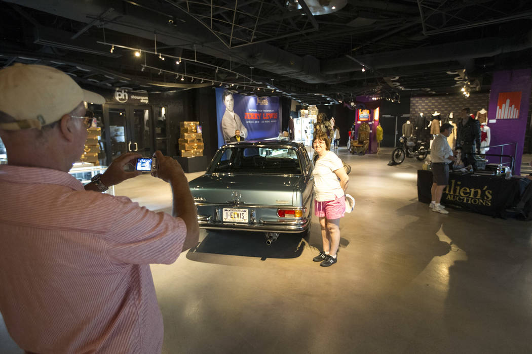 People pose next to a 1970 Mercedes-Benz 280 SEL purchased new by Elvis Presley and retained until his death on display as part of Julian's Auctions Hollywood Legends collection at Planet Hollywoo ...