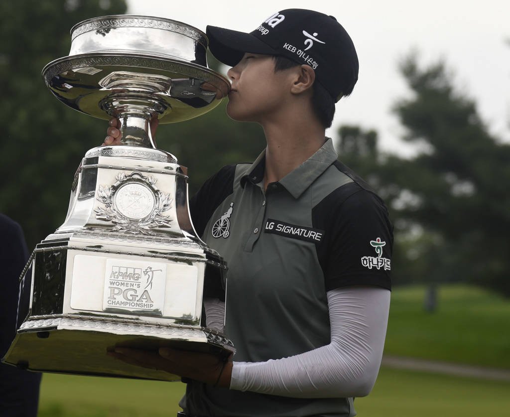 Sung Hyun Park, of South Korea, kisses the championship trophy after making a birdie on the second hole of a playoff on the 16th hole to win the KPMG Women