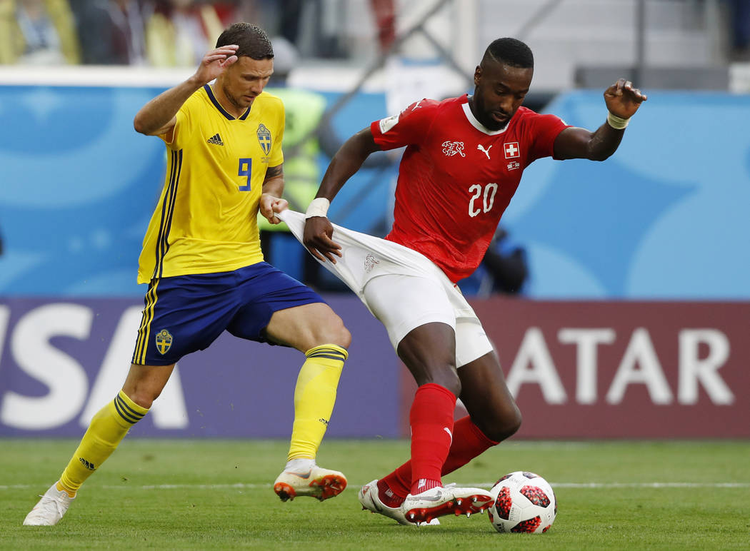Sweden's Marcus Berg, left, battles for the ball with Switzerland's Johan Djourou during the round of 16 match between Switzerland and Sweden at the 2018 soccer World Cup in the St. Petersburg Sta ...