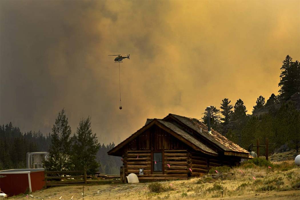 In this Monday, July 2, 2018 photo, a helicopter returns for water after making a water drop on a wildfire near Fairplay, Colo. The fire is burning about 20 miles south of Fairplay. Because of th ...