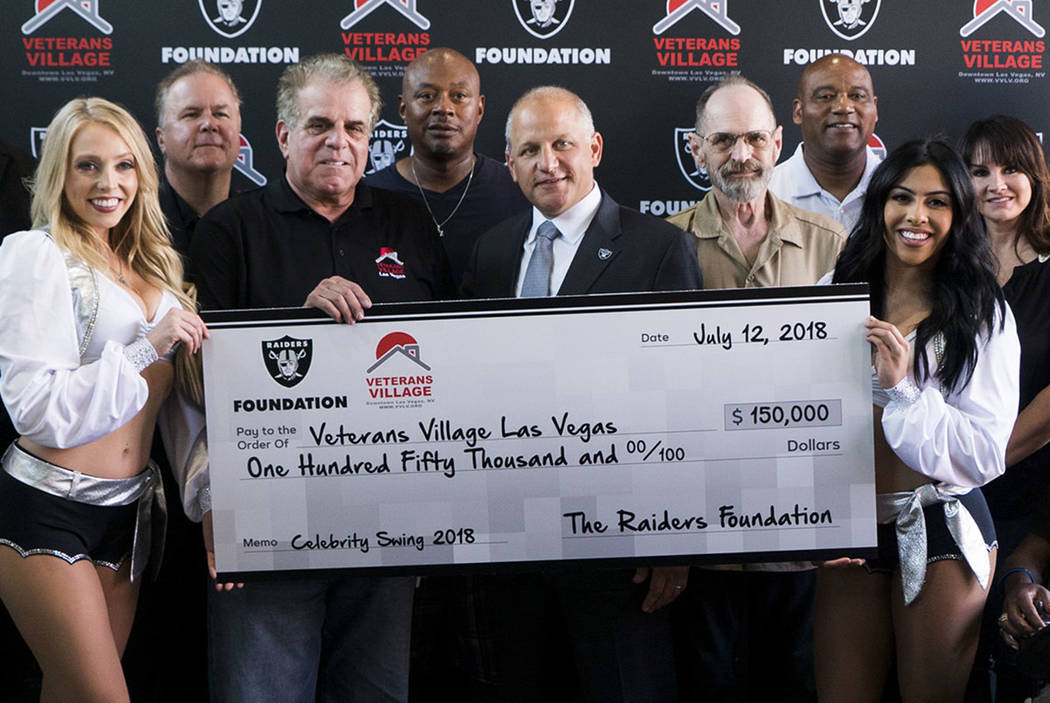 Veterans Village CEO and founder Arnold Stalk, center left, holds check provided by Raiders President Marc Badain, center right, at Veterans Village II in Las Vegas, Thursday, July 12, 2018. (Marc ...
