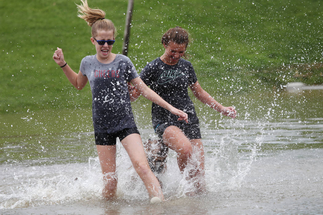 Terrylin Lemon, 12, left, and Makenzie Crider, 12, play in the water after a rain storm flooded the park off Wagonwheel Drive and Old Vegas Trail near U.S. Highway 95 in Henderson, Thursday, July ...