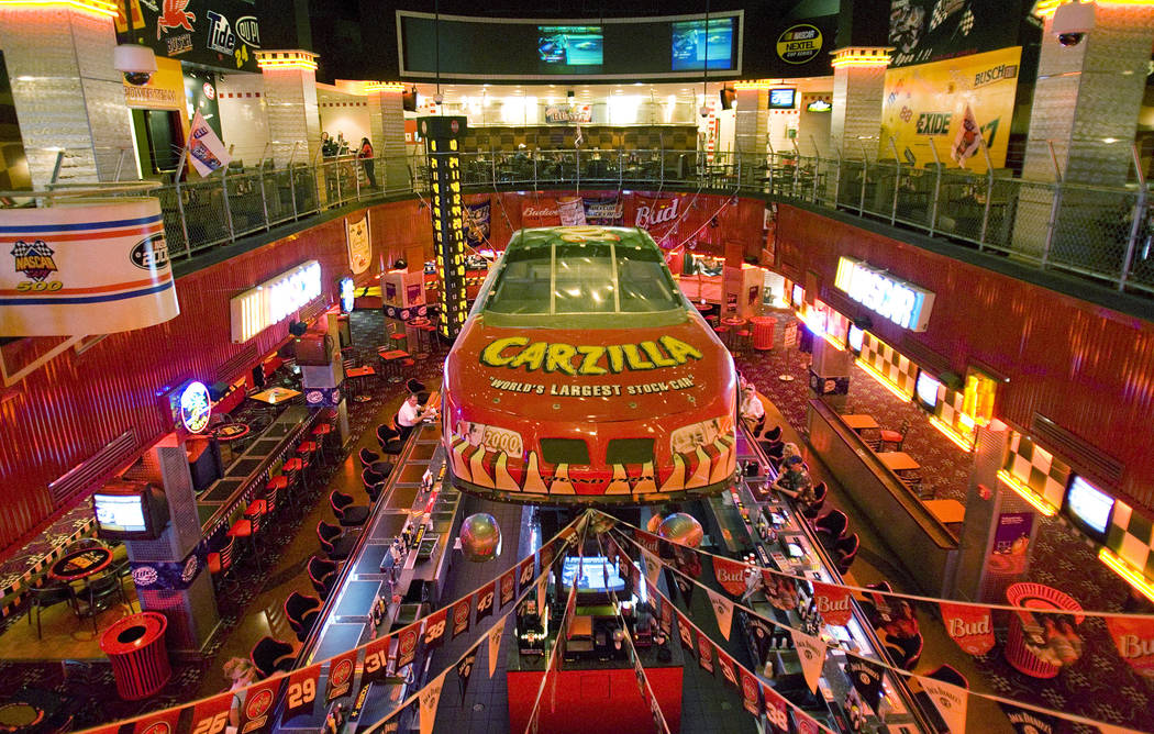 A scale NASCAR racing car is suspended above a bank of slot machines at The NASCAR Cafe inside ...