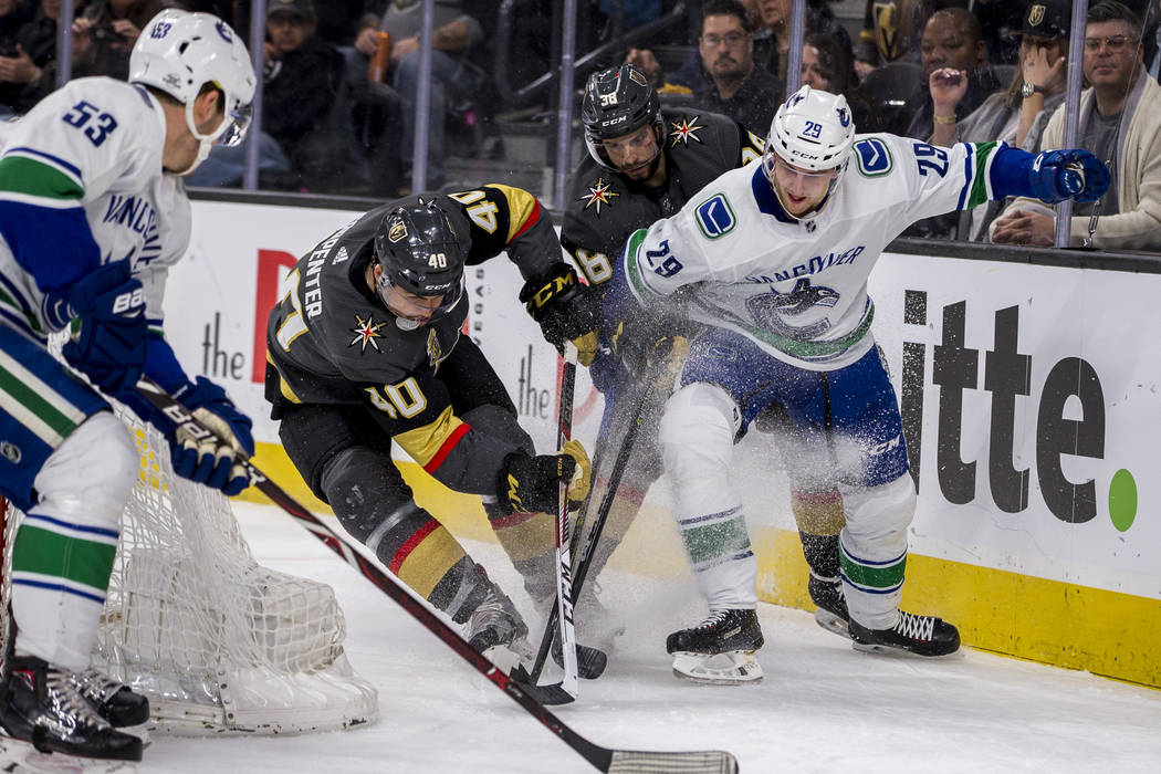 Golden Knights center Ryan Carpenter (40), Golden Knights right wing Tomas Hyka (38), Vancouver Canucks defenseman Philip Holm (29) and Vancouver Canucks center Bo Horvat (53) battle for the puck ...