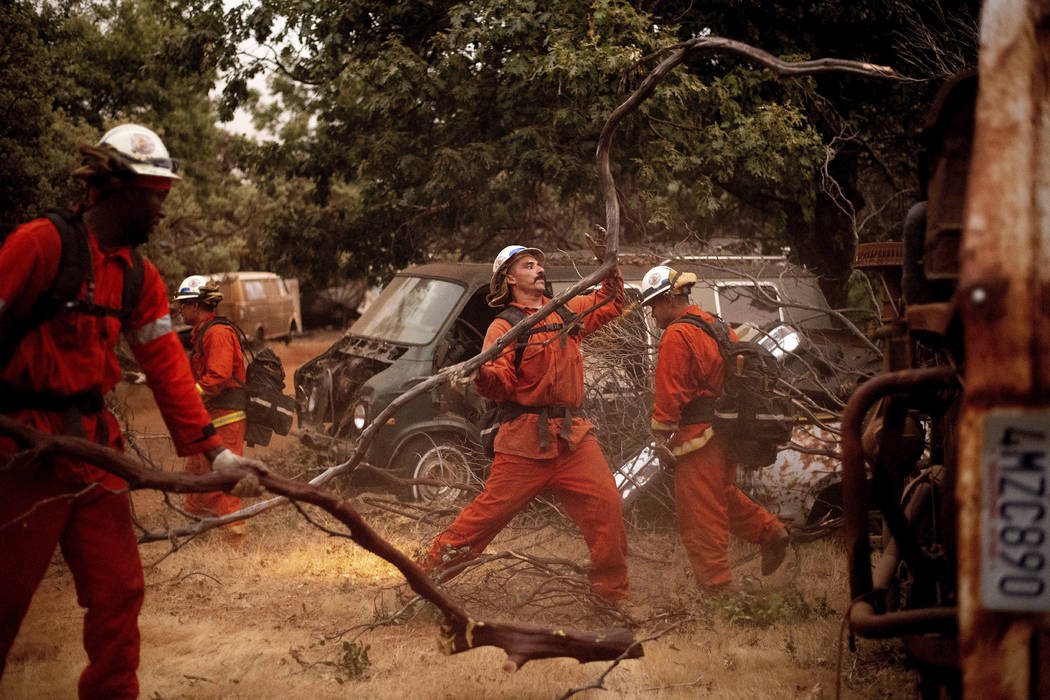 Inmate firefighters clear brush to create a fire break while battling the Ferguson Fire in unincorporated Mariposa County, Calif, on Monday, July 16, 2018. (AP Photo/Noah Berger)