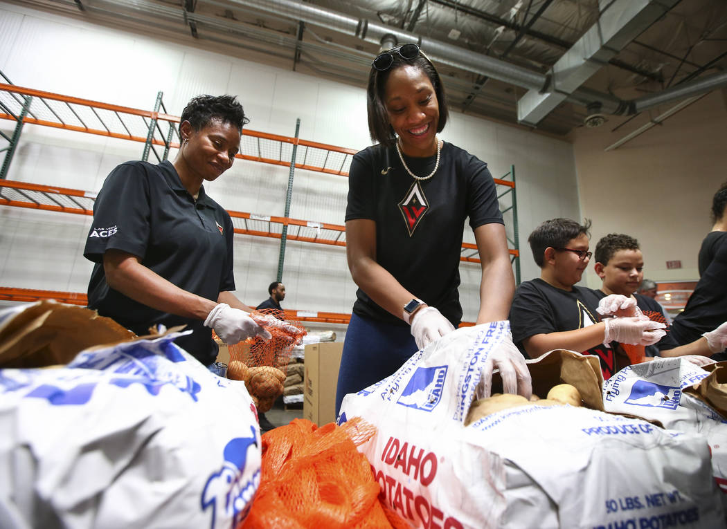 Las Vegas Aces assistant coach Vickie Johnson, left, and player A'ja Wilson package potatoes to be part of meal packages for residents in need at the Three Square food bank in Las Vegas on Tuesday ...