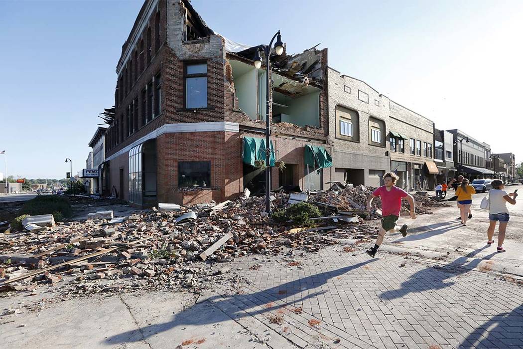 A local resident runs past a tornado-damaged building on Main Street, Thursday, July 19, 2018, in Marshalltown, Iowa. Several buildings were damaged by a tornado in the main business district in t ...