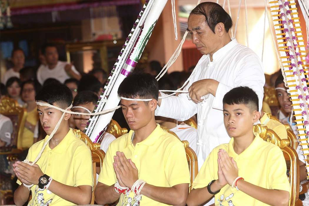 Soccer coach Ekkapol Janthawong, center, and members of the rescued soccer team attend a Buddhist ceremony that is believed to extend the lives of its attendees as well as ridding them of dangers ...