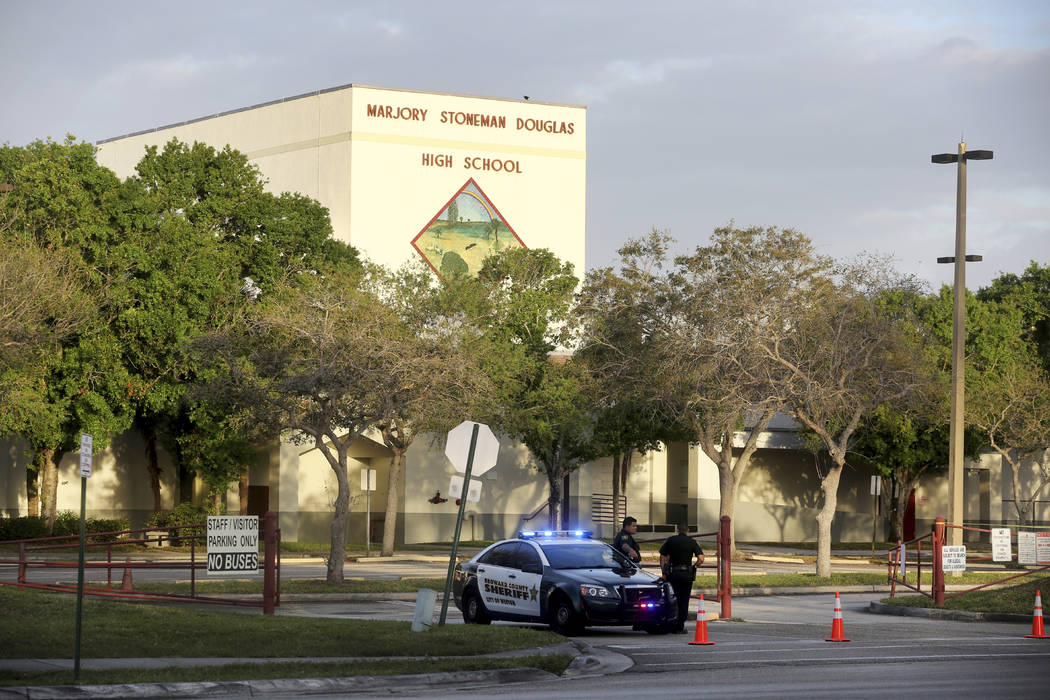 In this Feb. 23, 2018 file photo, police watch the entrance of a parking lot at Marjory Stoneman Douglas High School in Parkland, Fla. where teachers and administrators returned for the first time ...