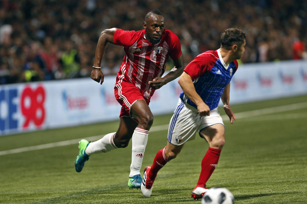 Former Olympic and Jamaican sprinter Usain Bolt, left, challenges for the ball with France's Bixente Lizarazu during a charity soccer match between members of the 1998 World Cup winning French tea ...