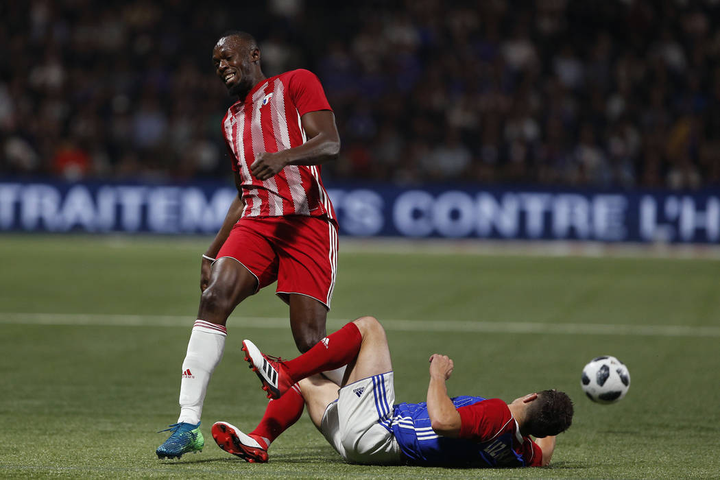 Former Olympic and Jamaican sprinter Usain Bolt, left, is tackled by Bixente Lizarazu during a charity soccer match between members of the 1998 World Cup winning French team and a team of internat ...