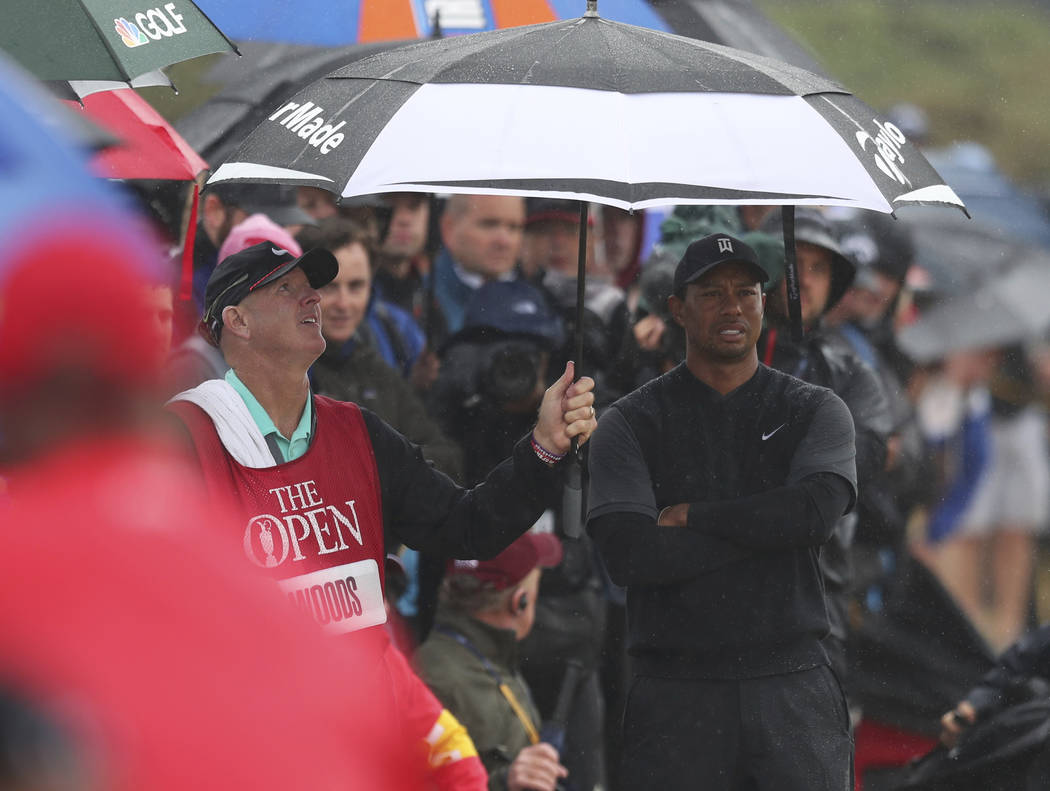 Caddie Joe Lacava shelters Tiger Woods of the US under an umbrella as he waits to play out of the rough on the 7th hole during the second round of the British Open Golf Championship in Carnoustie, ...