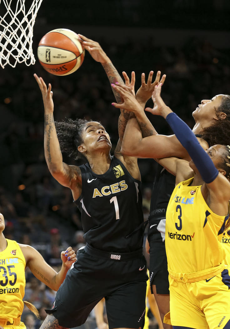 Las Vegas Aces forward Tamera Young (1) pulls in the rebound over Indiana Fever guard Tiffany Mitchell (3) and teammate Jaime Nared (31) during the second half of a WNBA basketball game at the Man ...