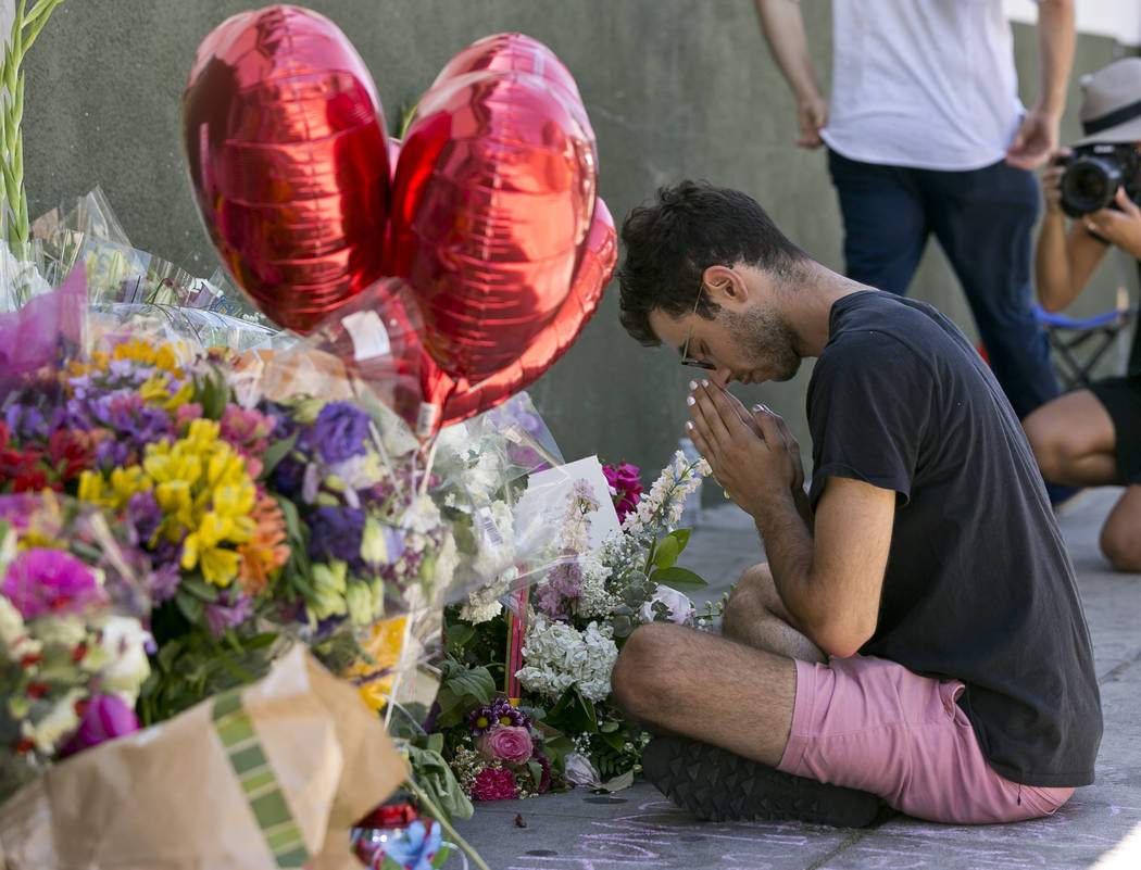 ADDS TO CLARIFY CORADO WAS SHOT TO DEATH IN A GUNFIGHT BETWEEN A GUNMAN AND POLICE - Paolo Singer, 27, a Silver Lake resident, prays at a makeshift memorial of flowers, candles and notes growing o ...