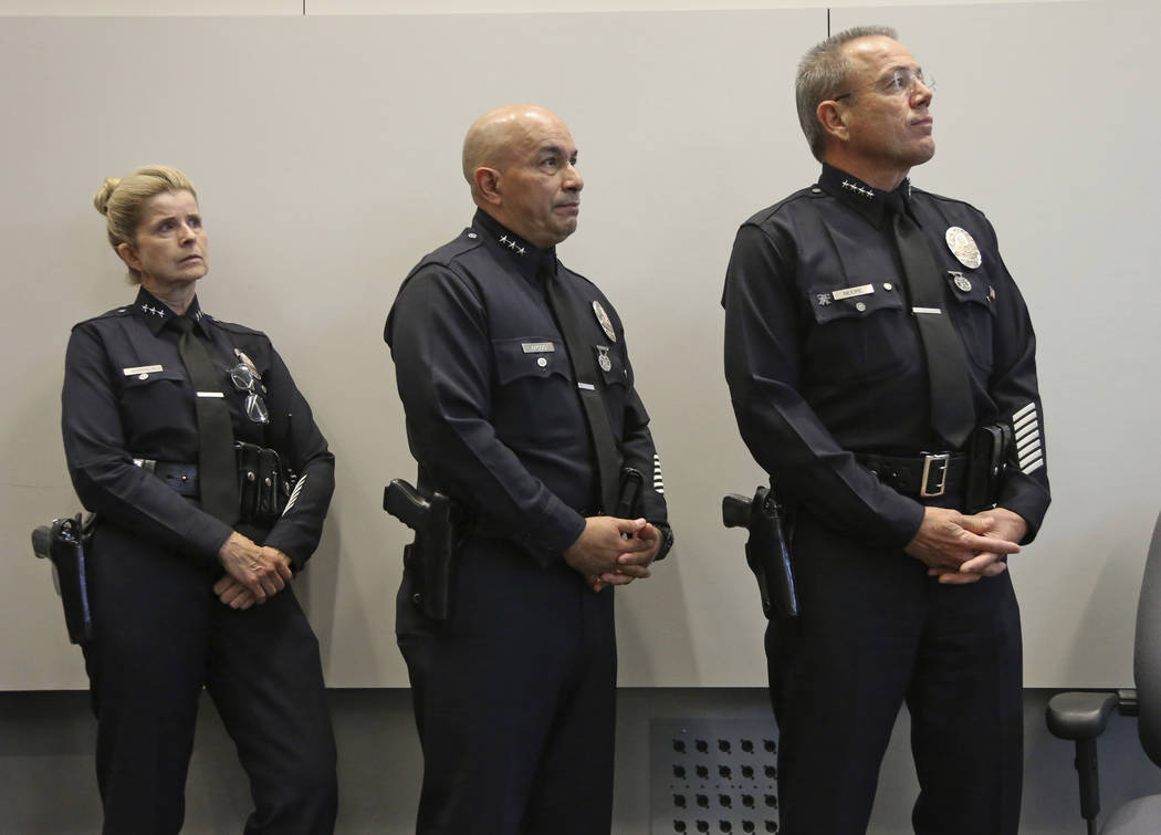 Los Angeles Police Chief Michel Moore, right, and others watch a video from police body and car cameras during news conference at police headquarters Tuesday, July 24, 2018, in Los Angeles, where ...