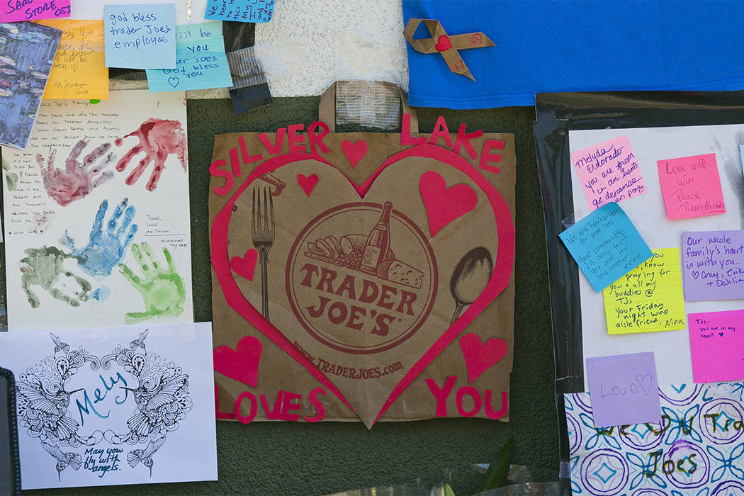 A heart-shaped card made with a recycled Trader Joe's paper bag is posted by a makeshift memorial of flowers, candles and notes on the sidewalk outside the Silver Lake Trader Joe's store in Los An ...
