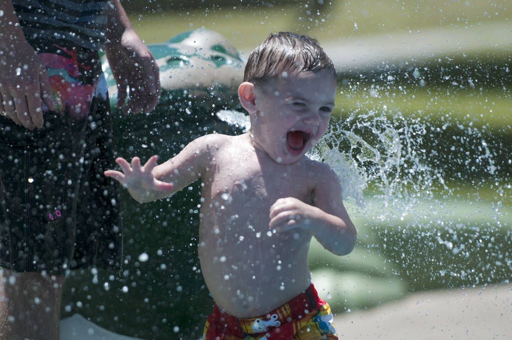 Matthew Perkins, 1, plays in the splash pad with his father Nick at the Centennial Hills Park in Las Vegas on Thursday, June 27, 2013. Excessive heat warnings are in place due to the rise of tempe ...