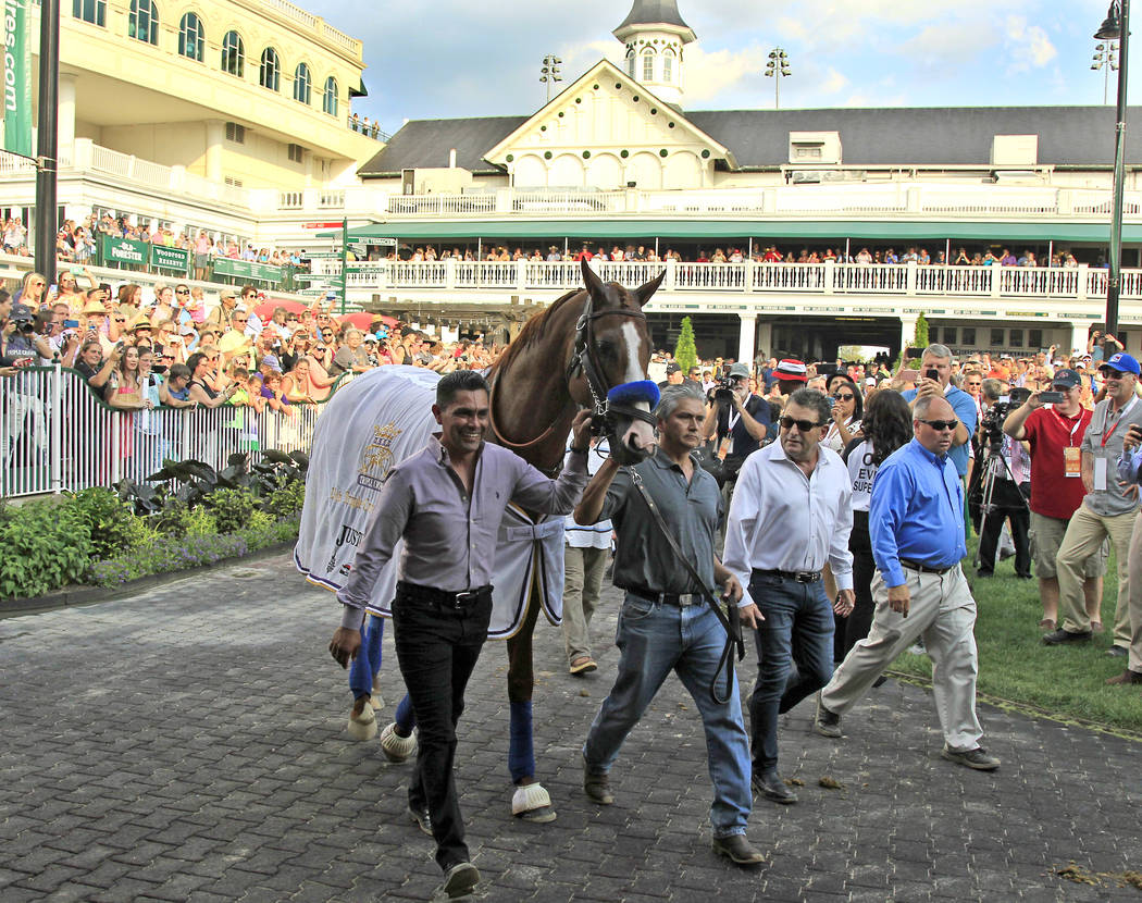 In this June 16, 2018, file photo, Triple Crown champion Justify, led by exercise rider Humberto Gomez, left, and groom Eduardo Luna, second from left, is the center of attention in the paddock at ...