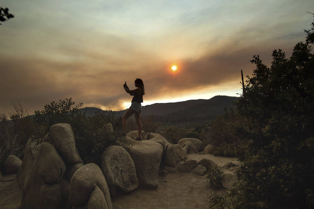 Mara Schumann photographs a plume of smoke from the Ferguson Fire in Yosemite National Park, Calif., on Tuesday, July 24, 2018. Parts of the park, including Yosemite Valley, will close Wednesday a ...